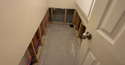 Unfinished basement bathroom during renovation with exposed framing and concrete floor