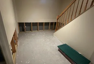 Unfinished basement with exposed wall framing and wooden staircase before drywall