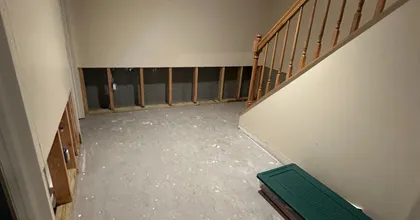 Unfinished basement with exposed wall framing and wooden staircase before drywall