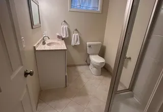 Freshly painted beige basement bathroom with vanity, toilet and glass shower