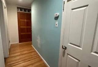 Hallway with a freshly painted teal accent wall, white door and hardwood floor