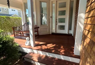 Front porch with richly stained mahogany decking, white columns and cedar shingles